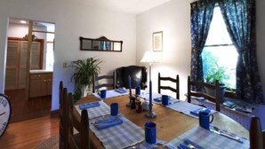 A dining area with a wooden table set for four, blue placemats, and a lamp. - Chesapeake Inn of Lenox (Lenox)