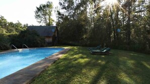 A swimming pool with a grassy area and lounge chairs. - Chesapeake Inn of Lenox (Lenox)