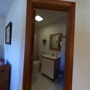 A narrow hallway leading to a bathroom with a toilet, sink, and mirror. - Chesapeake Inn of Lenox (Lenox)