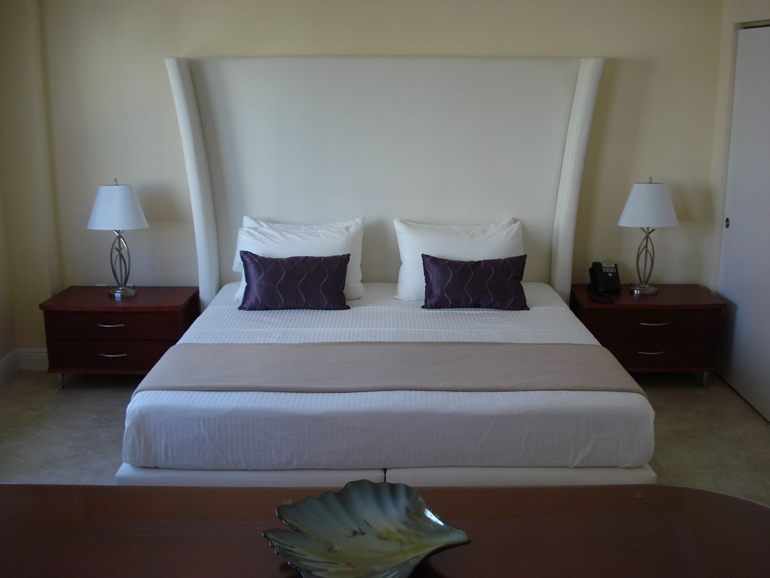 A neatly arranged hotel room with a large bed, two bedside tables, and a decorative bowl on the bed.