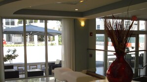 A hotel lobby with a large glass door, a white sofa, and a red vase on a table. - Westover Arms Hotel  (Miami Beach)