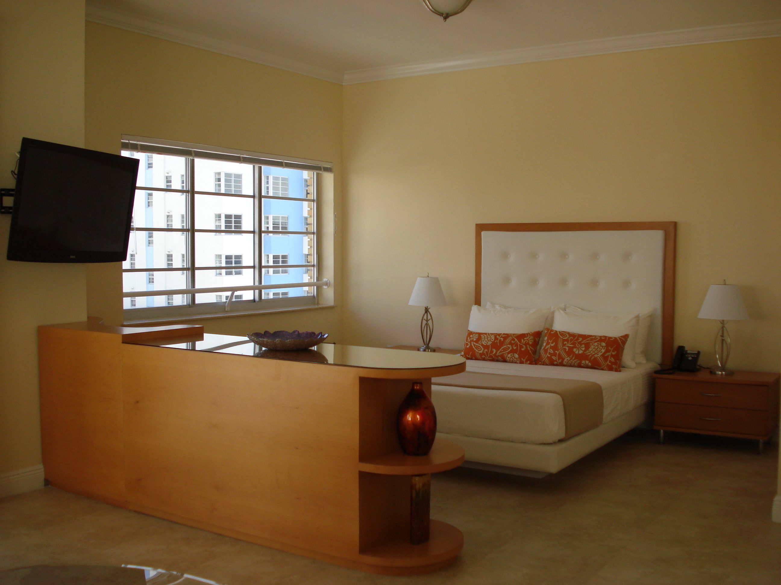Una habitación de hotel con una cama, mesitas de noche, un escritorio y un televisor.