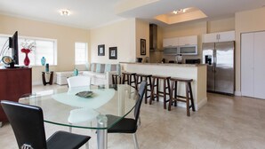 A modern kitchen with a central island, bar stools, and a glass dining table. - Westover Arms Hotel  (Miami Beach)