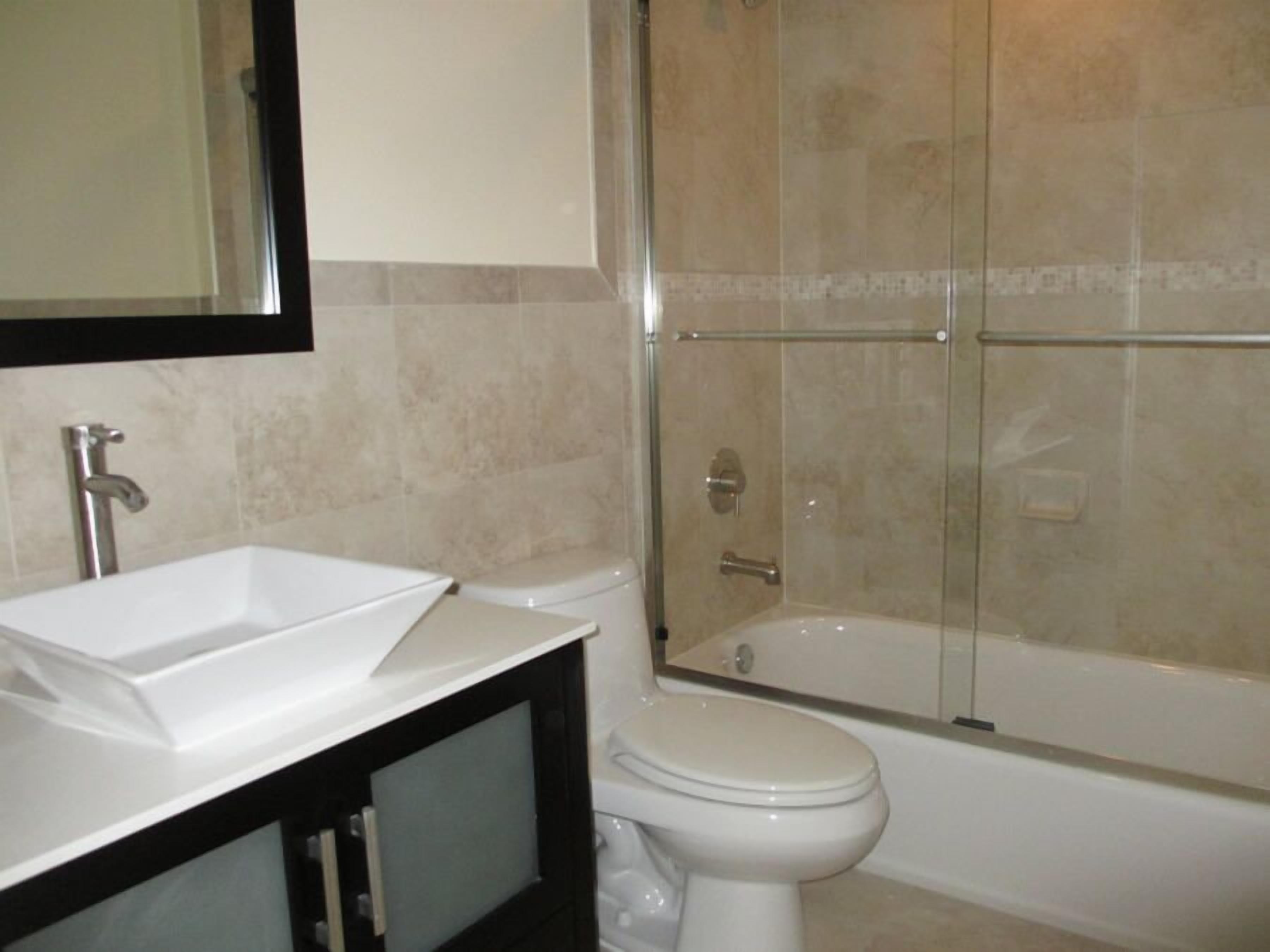 A bathroom with a white sink, a toilet, and a glass-enclosed shower area.