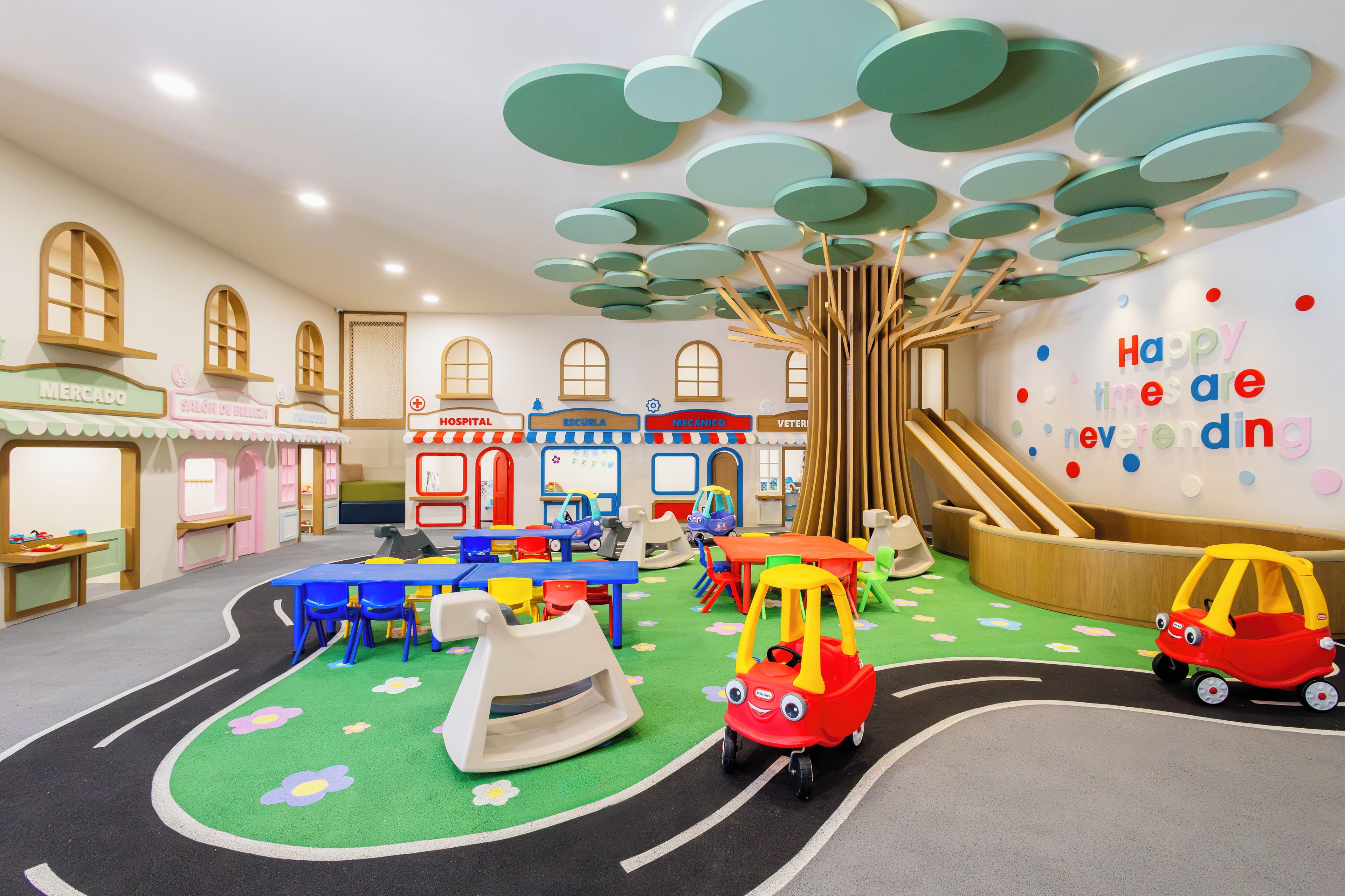 A children's play area with a slide, tables, chairs, and a play kitchen set.