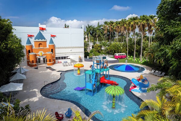 Parque aquático com área de recreação temática de castelo, piscina e serviço de transporte por ônibus.
