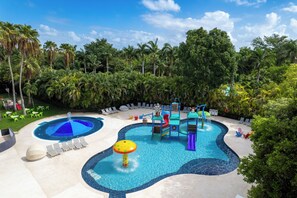 Ein Poolbereich mit Wasserrutschen, Liegestühlen und Palmen.