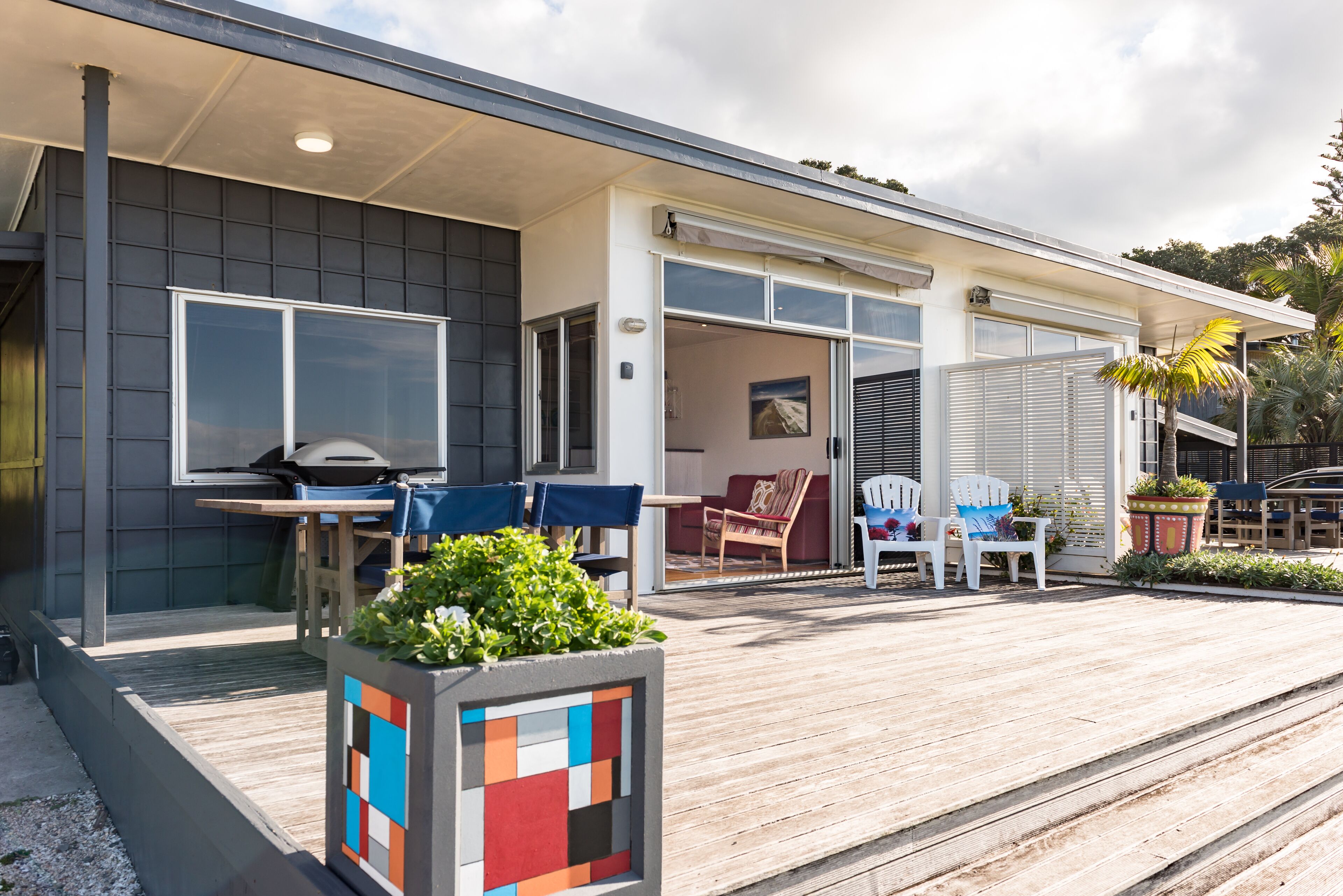 A modern house with a covered patio, outdoor seating, and a barbecue area.