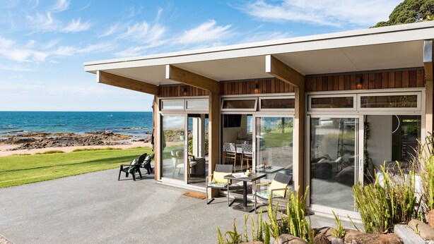 Une maison moderne dotée d’une terrasse offrant une vue sur l’océan.