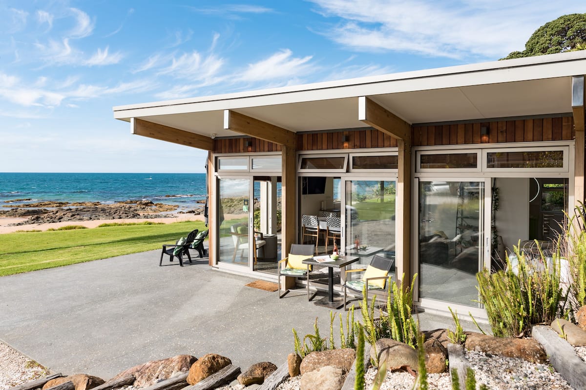 A modern house with a patio overlooking the ocean.