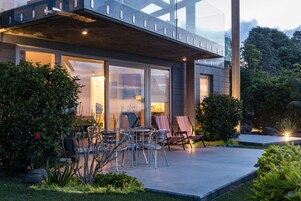 A modern house with a patio, outdoor furniture, and a well-maintained garden.
