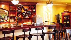 A bar area with wooden chairs, a wine rack, and a counter with bottles and glasses.