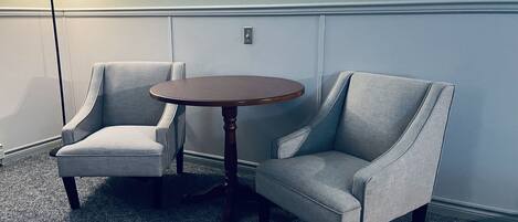 A room with two grey armchairs and a round wooden table.