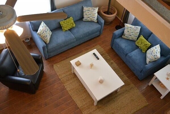 A living room with a blue sofa, a white coffee table, and a black leather chair.