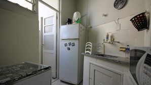 Een kleine keuken met een koelkast, magnetron en fornuis.