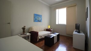 Een kamer met een bed, een bureau, een stoel, een televisie en een raam.