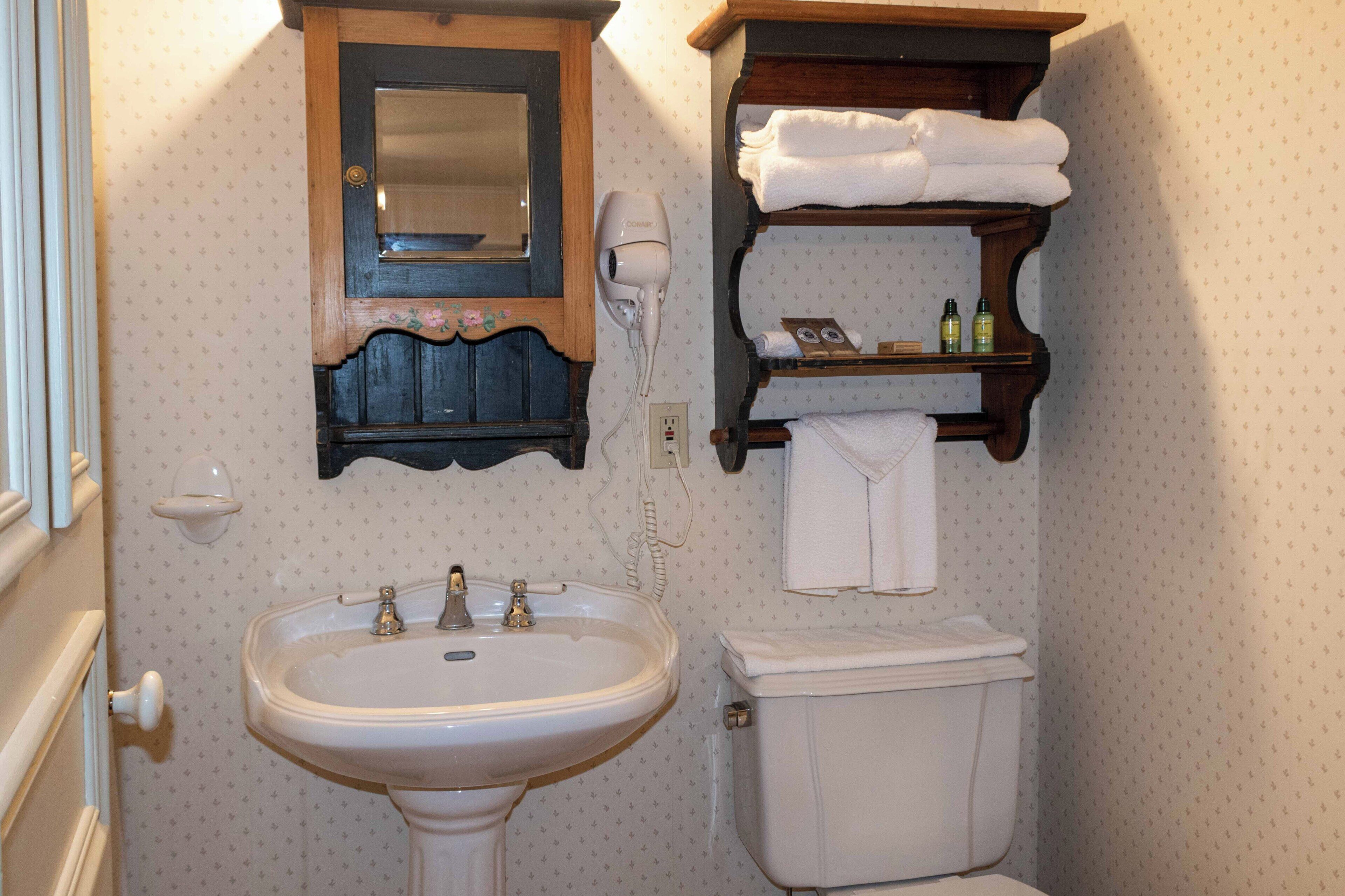 Un baño con lavamanos, inodoro, espejo y toallero.