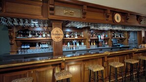 A bar area with a Guinness sign, bar stools, and shelves of bottles and glasses. - Auberge Lakeview Inn (Lac-Brome)