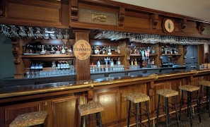 A bar area with a Guinness sign, bar stools, and shelves of bottles and glasses. - Auberge Lakeview Inn (Lac-Brome)