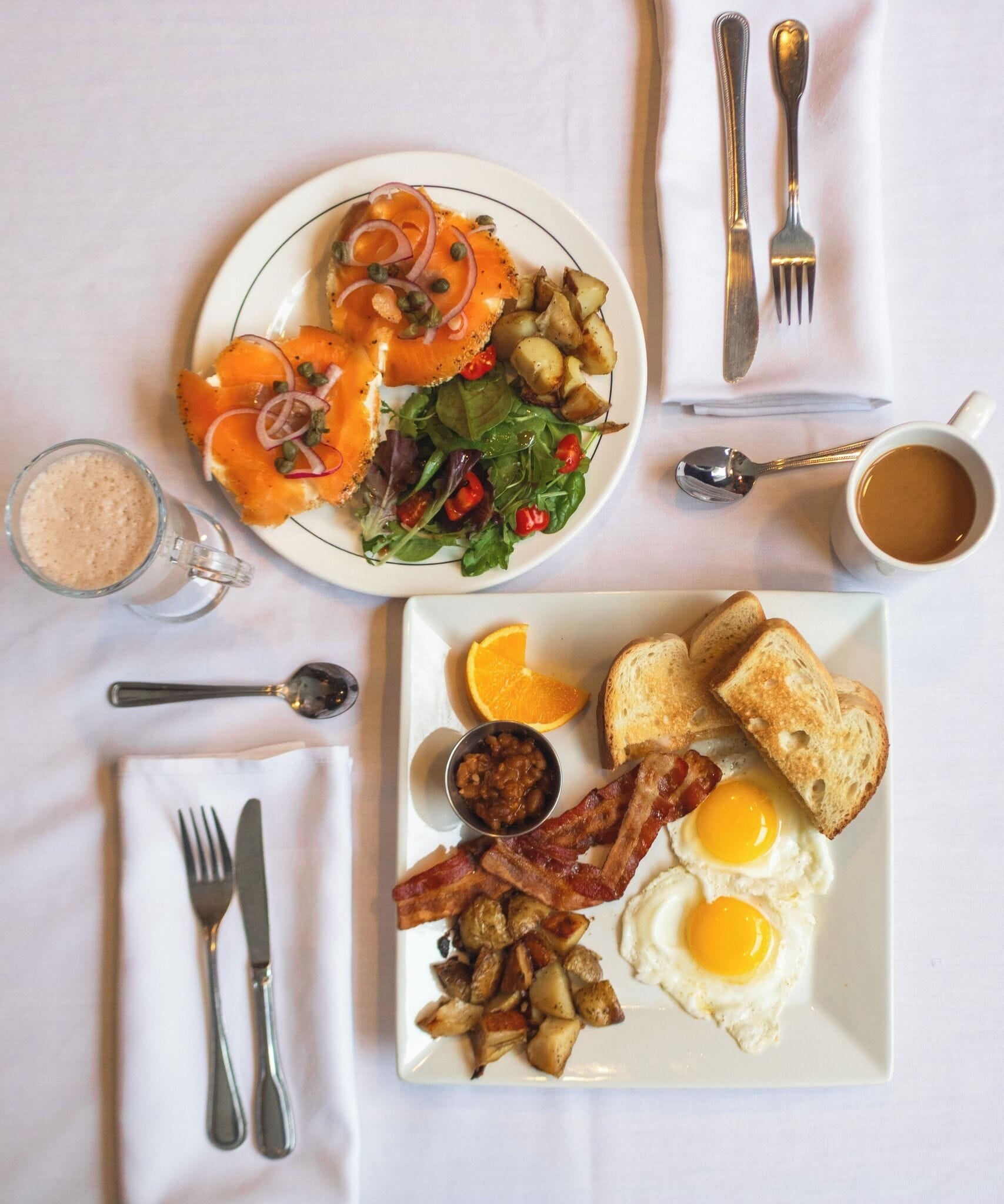 A breakfast plate with eggs, bacon, toast, and a side salad.