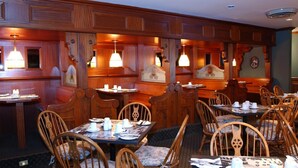 A restaurant with wooden paneling, pendant lighting, and a variety of seating options including booths and tables. - Auberge Lakeview Inn (Lac-Brome)