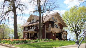 A two-story house with a front porch, a fire escape, and a well-maintained garden with colorful flowers.