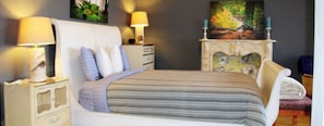 Classic bedroom with a large bed, two bedside tables, and a dresser featuring a mirror and decorative piece.