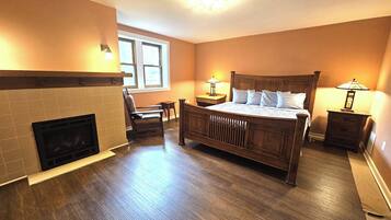 A bedroom with a wooden bed, a fireplace, and two bedside lamps.
