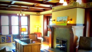 A cozy living room with a fireplace, wooden furniture, and a large window.
