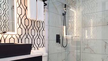 A modern bathroom with a black and white patterned wall, a glass shower enclosure, and a white toilet.