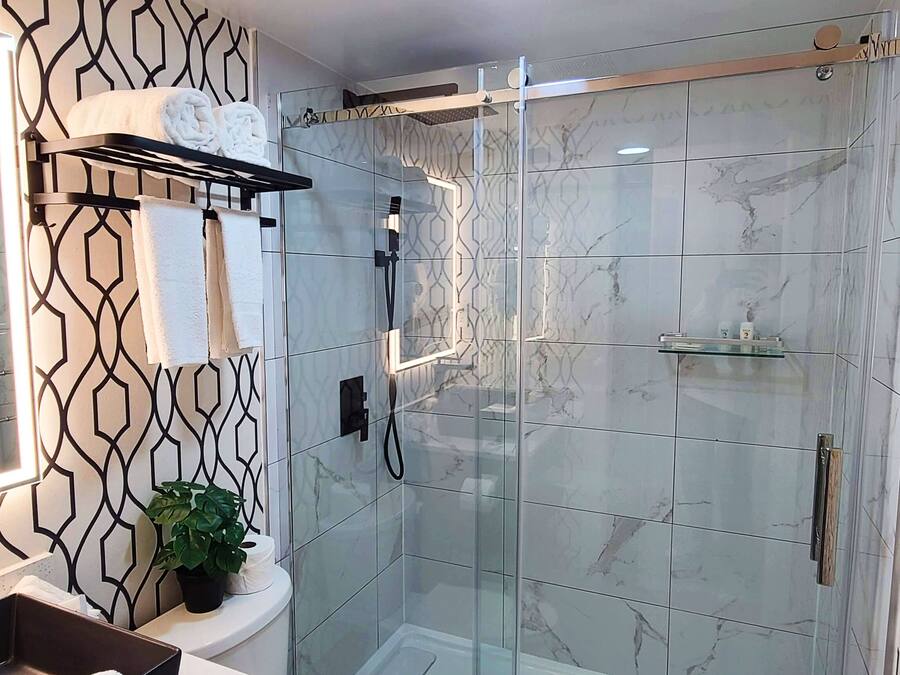 A modern bathroom with a glass-enclosed shower, a sink with a mirror, and a towel rack.