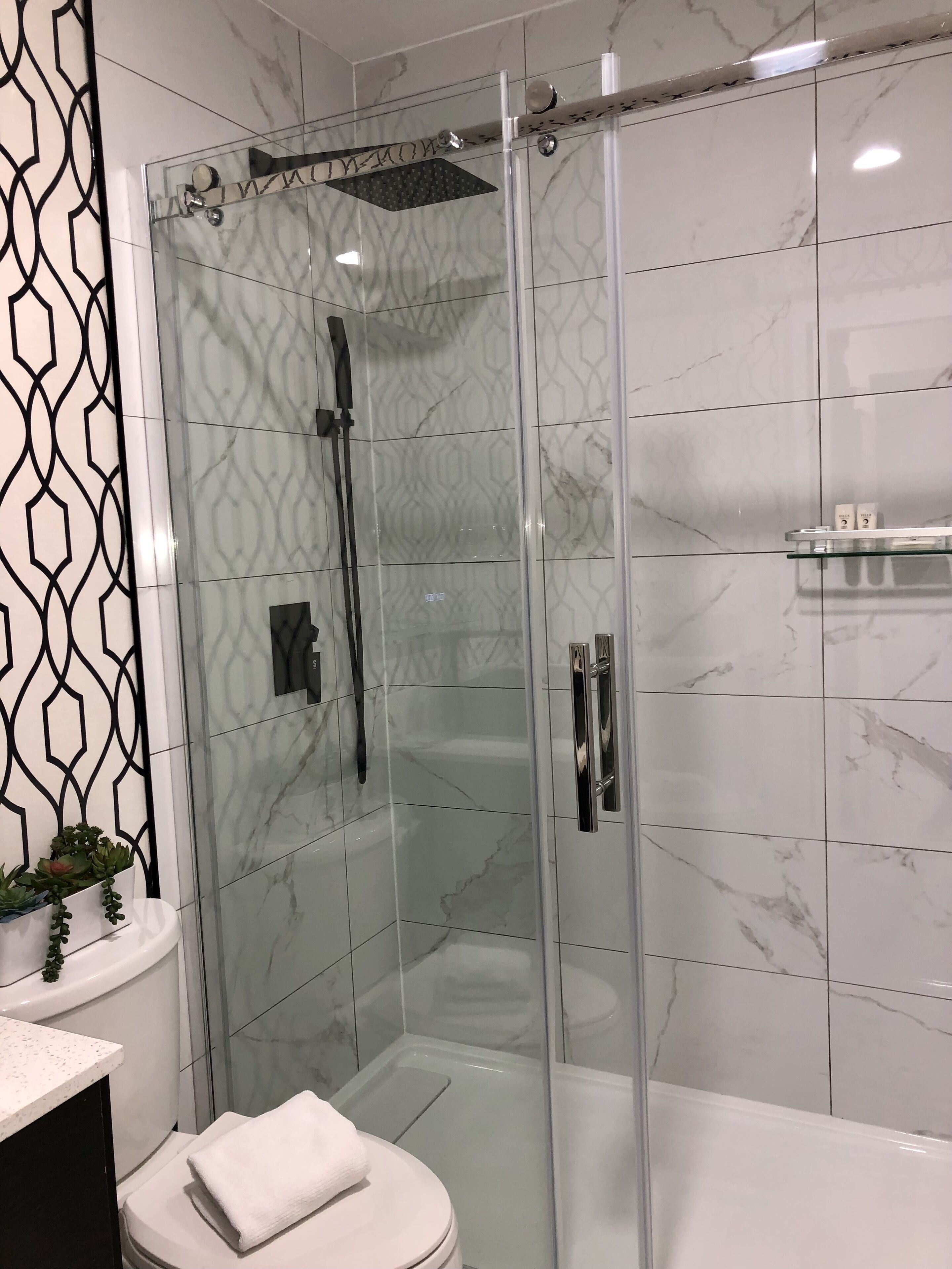 Un baño moderno con ducha de mampara de vidrio, inodoro y zona de lavamanos.