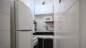 Uma cozinha compacta com armários brancos, micro-ondas, fogão e pia.