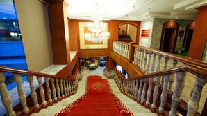 A grand staircase with marble steps and a red carpet leading to a second-floor landing.