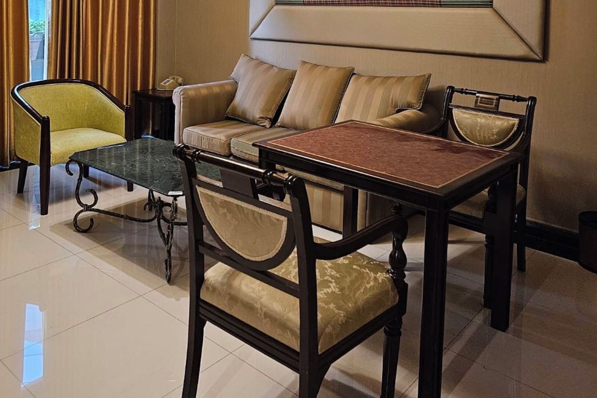 A room with a sofa, armchairs, a dining table, and a chandelier.