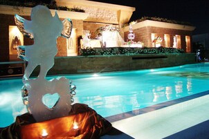 Una piscina al aire libre, sombrillas, sillones reclinables de piscina