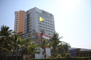 A multi-story hotel with a prominent 'KOSA' sign, palm trees, and a yellow flag. - Kosa Hotel & Shopping Mall (Khon Kaen)