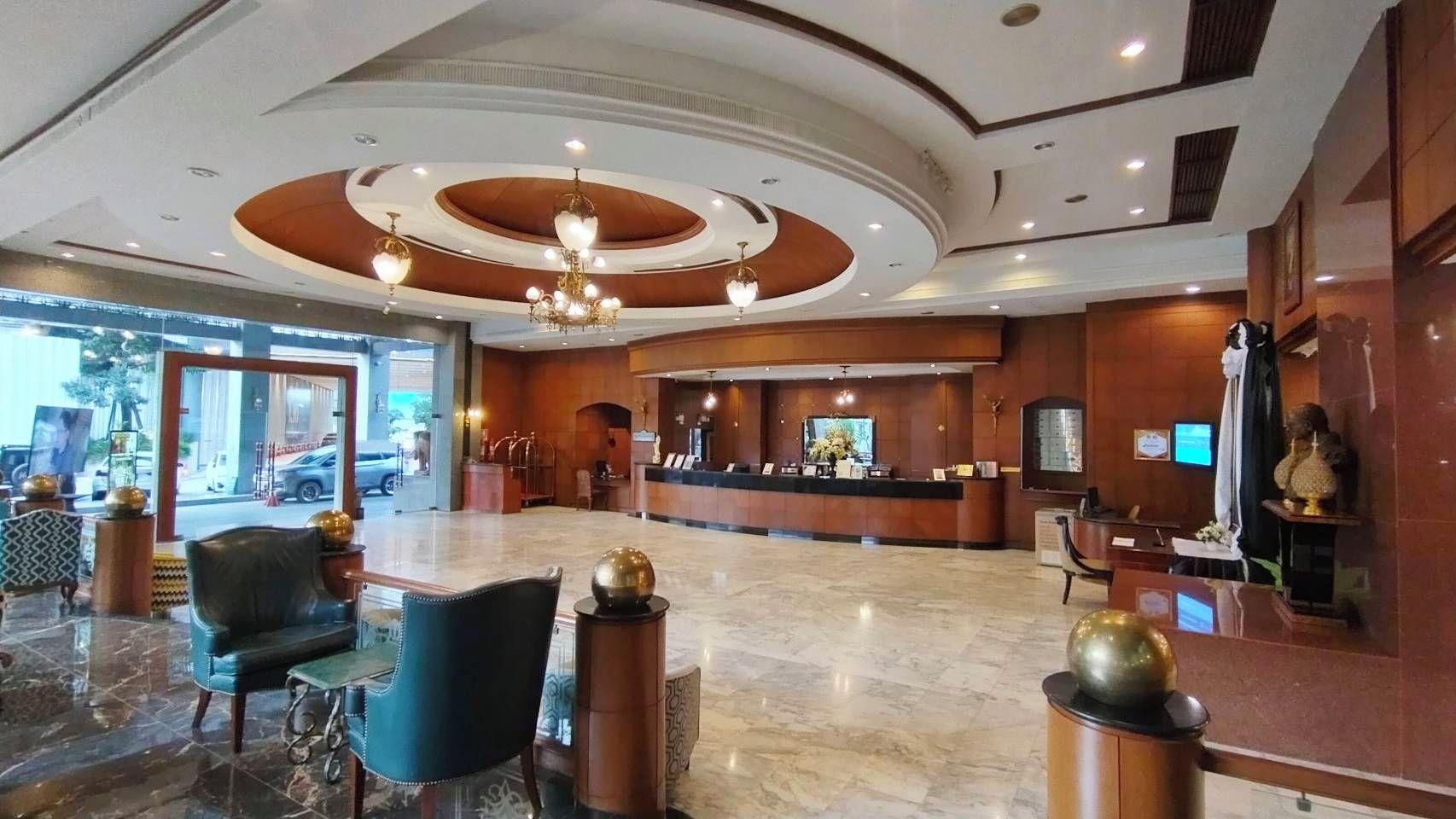A hotel lobby with a reception desk, seating area, and a large window overlooking the street.