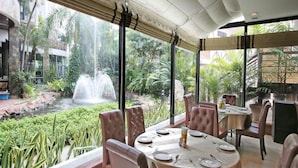 Un restaurante con vistas a un elemento acuático y abundante vegetación.
