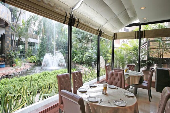 A restaurant with a view of a water feature and lush greenery. - Kosa Hotel & Shopping Mall (Khon Kaen)
