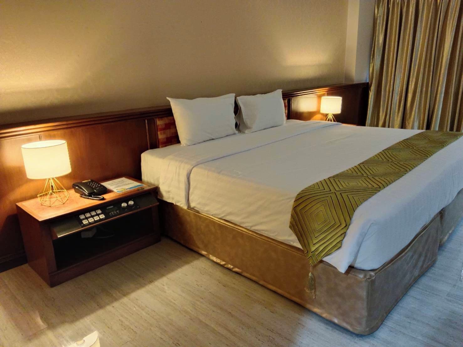 Ein Hotelzimmer mit Bett, Nachttischen, einer Lampe und einem Telefon.
