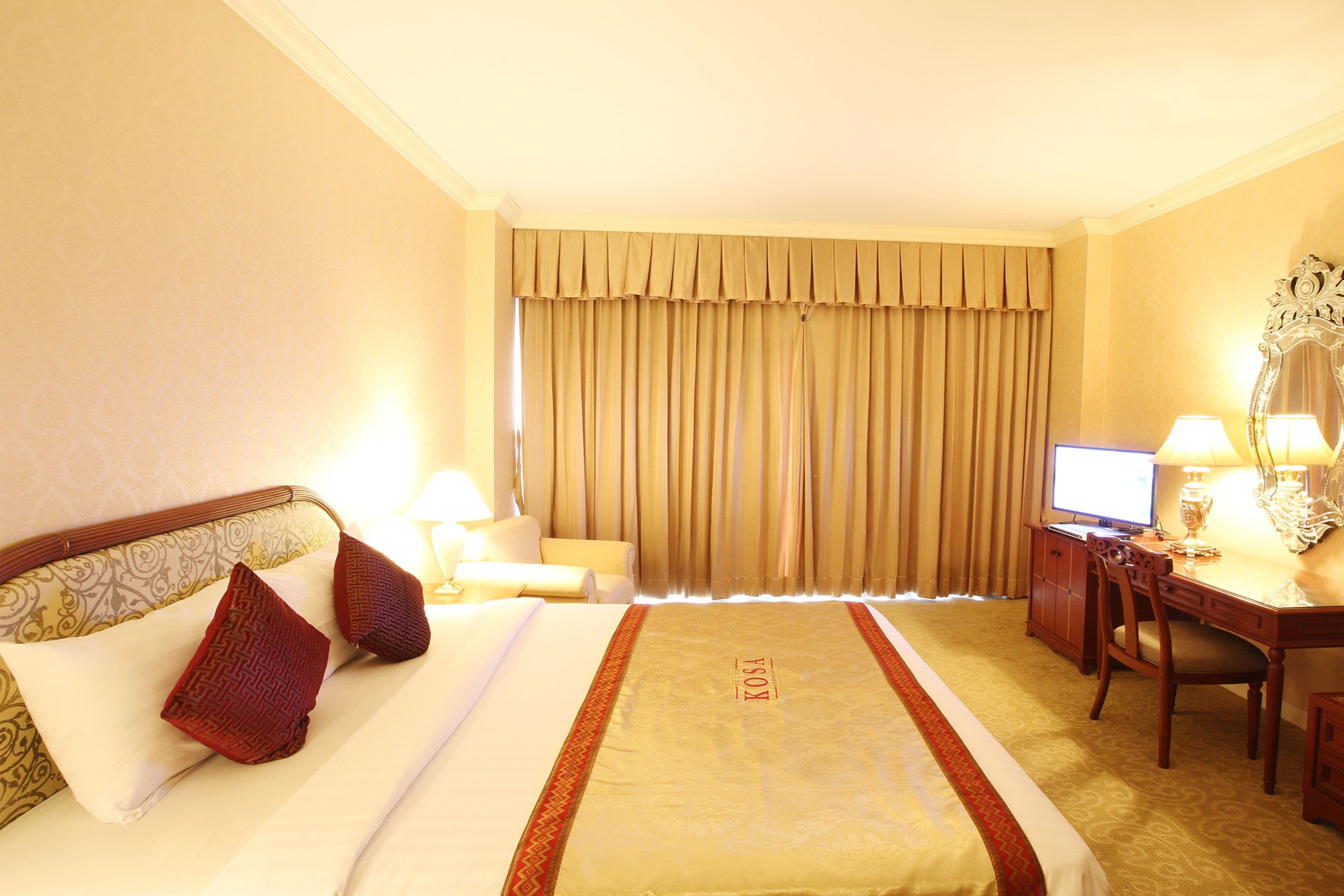 Une chambre d’hôtel équipée d’un lit, d’un bureau, d’une chaise, d’une télévision et d’une lampe.