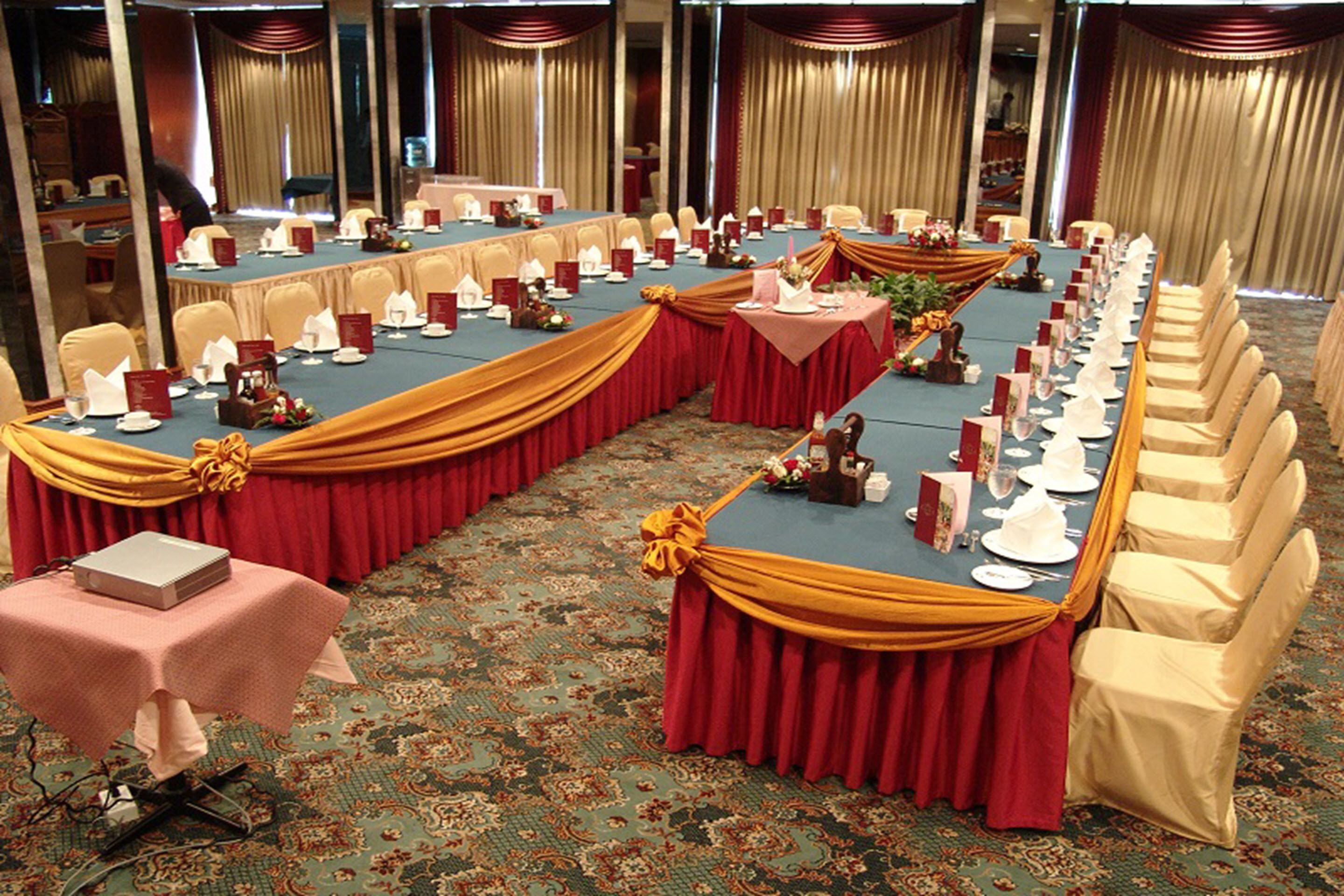 Un salón de conferencias con una larga mesa, sillas y un ordenador portátil sobre la mesa.