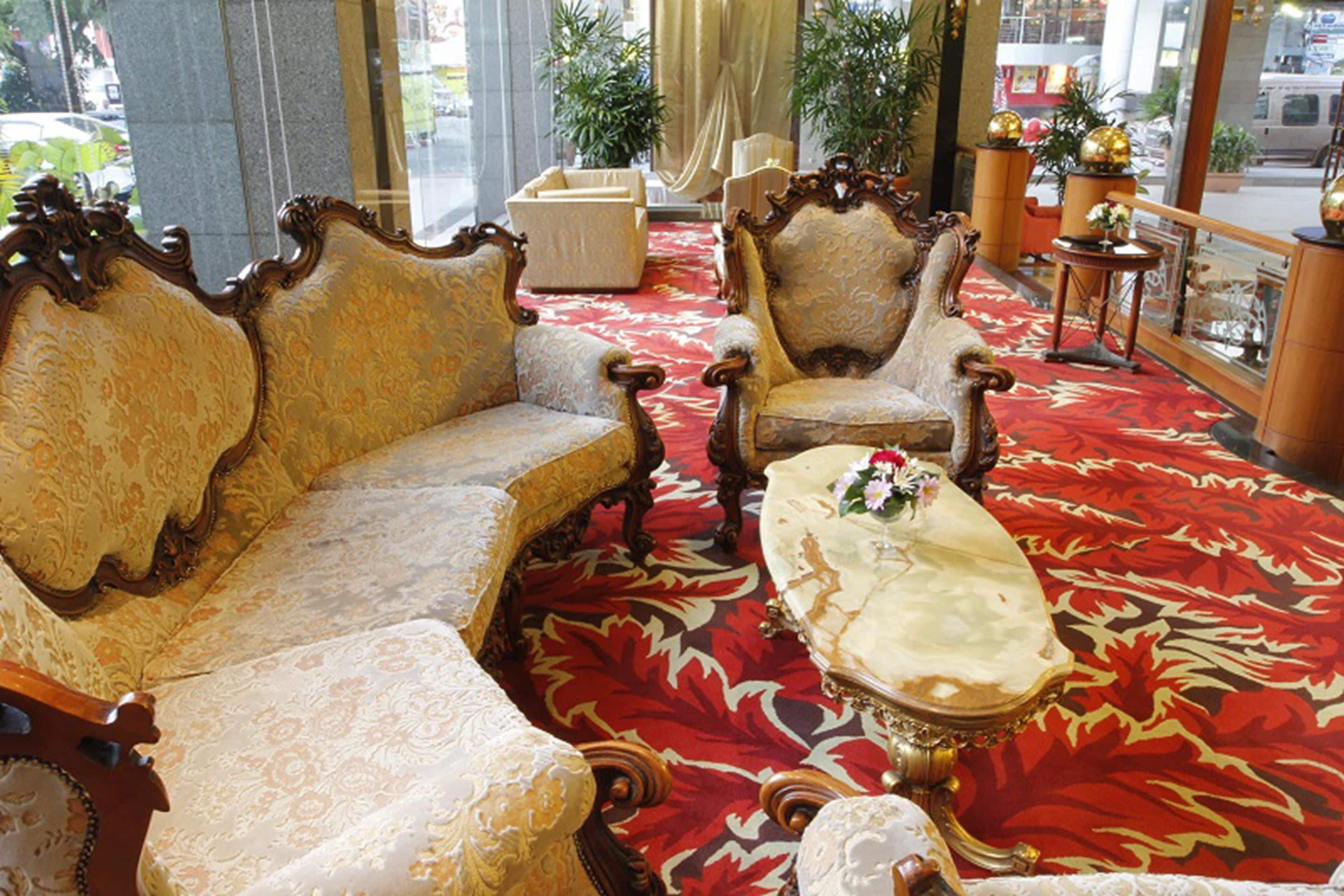 A luxurious room with ornate furniture, a red patterned carpet, and large windows.
