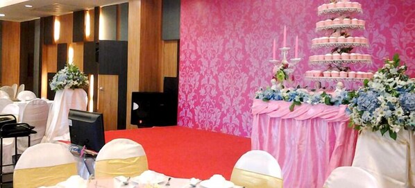 Zona de recepción de boda con un pastel de varios niveles, arreglos florales y alfombra roja.