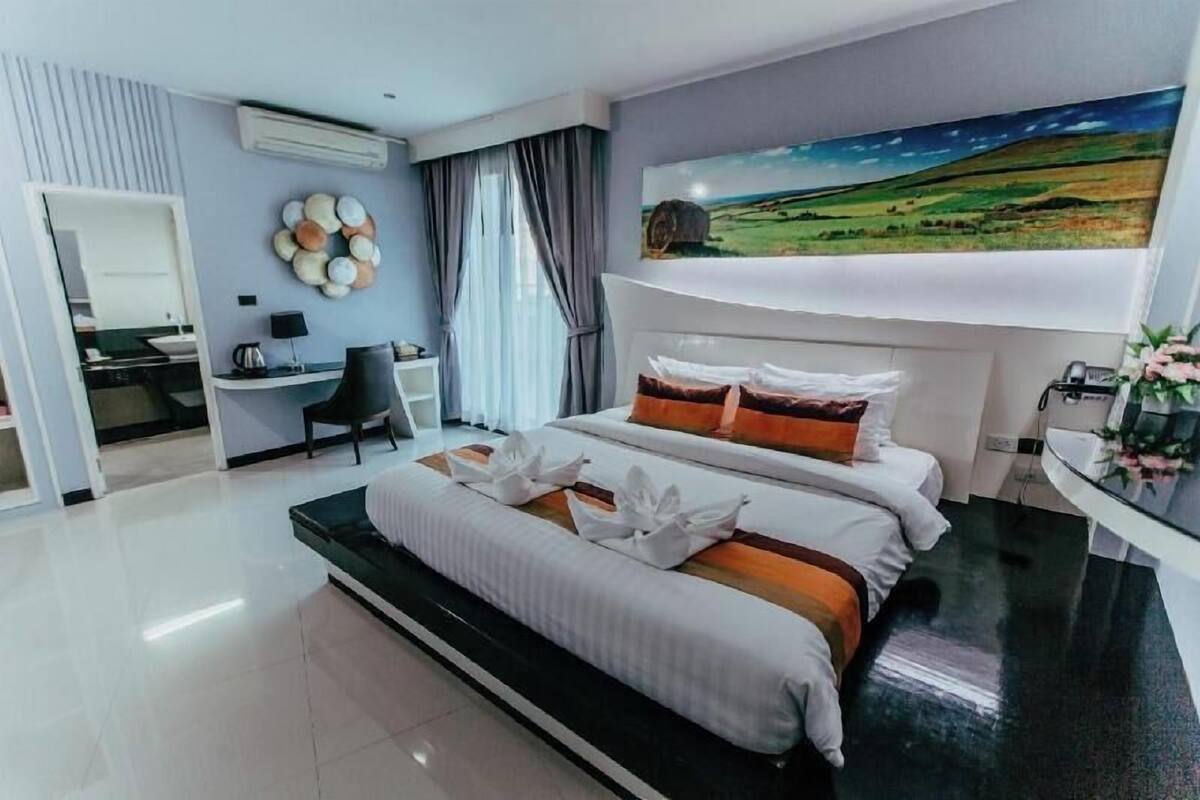Habitació d'hotel moderna amb llit, escriptori i un quadre de paisatge.