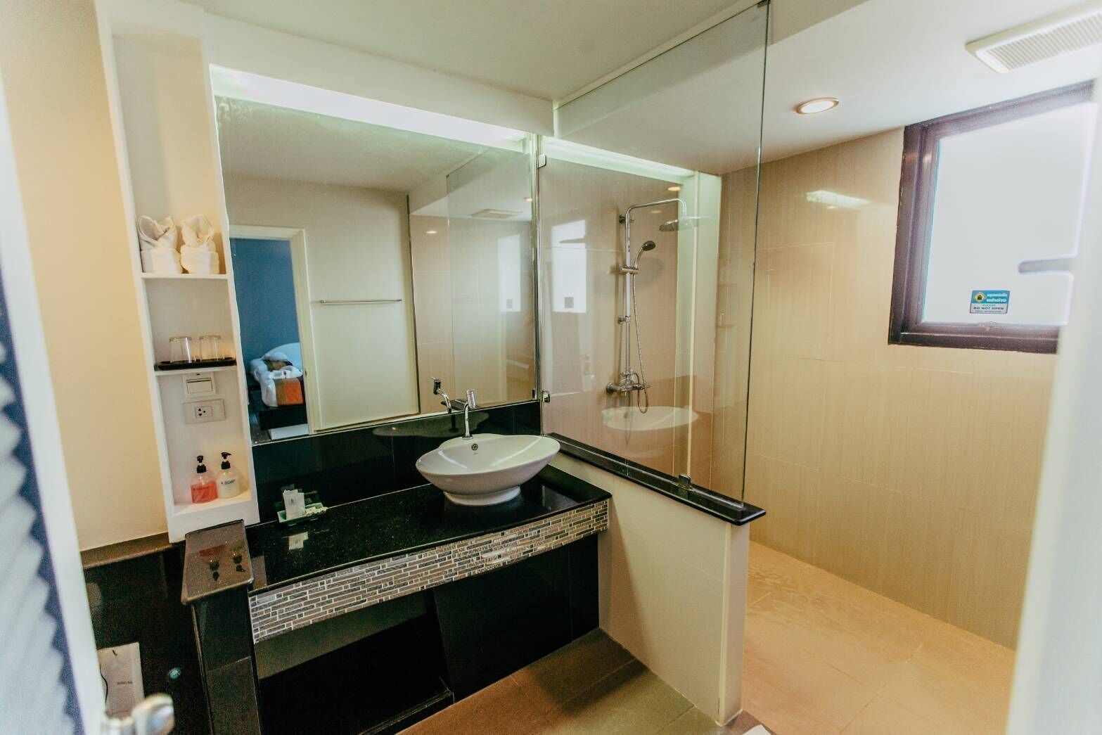 A modern bathroom with a black countertop, white sink, and a glass shower enclosure.
