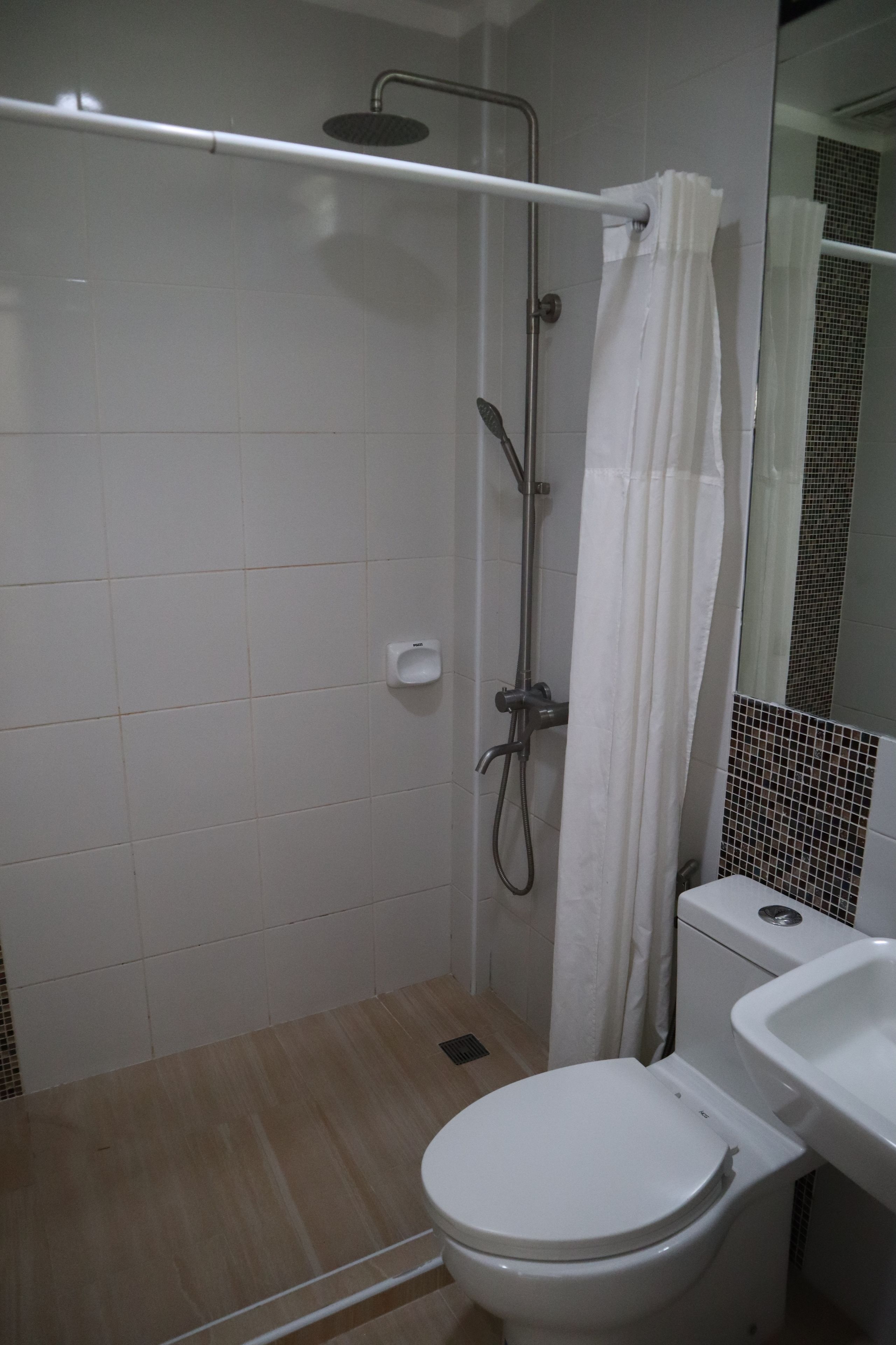 Een badkamer met douche, toilet en wastafel.