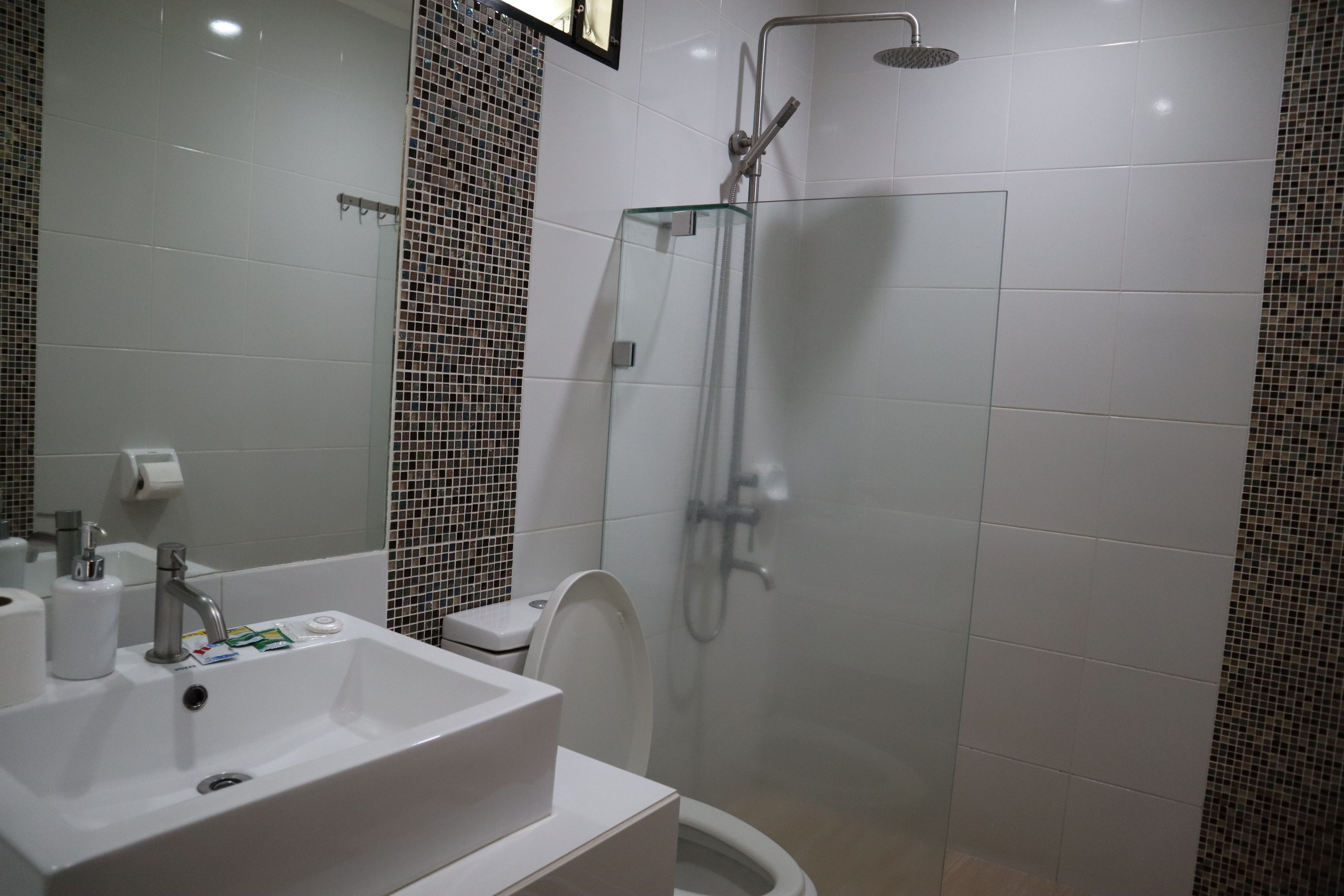 Ein modernes Badezimmer mit einer gläsernen Dusche, einem weißen Waschbecken und einer Toilette.