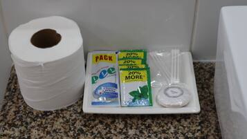 A bathroom sink area with a roll of toilet paper, a soap dish, and a pack of dental floss.